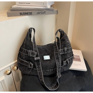 Detail of black washed denim messenger bag with silver metal plate and buckle straps