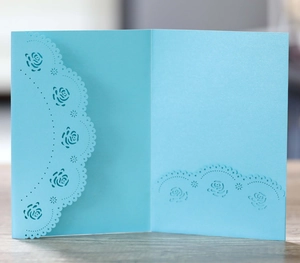 Gros plan des motifs de roses découpés au laser sur l'invitation de mariage bleu ciel