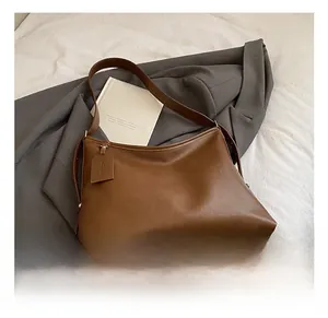 Detailed view of large brown faux leather tote bag with silver bottom studs and zipper