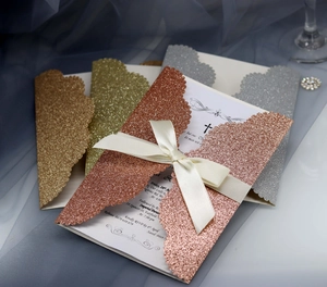 Detailed laser-cut wedding invitations with glitter finish and satin ribbon bow