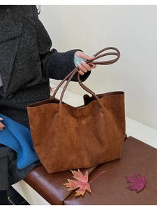Détail d'un grand sac cabas minimaliste en daim marron foncé avec de fines poignées