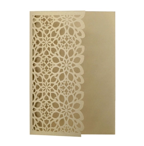Detail of laser-cut champagne gold wedding invitation card with mandala flower patterns