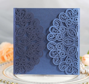 Detail showing deep blue laser cut wedding invitation with intricate lace floral pattern