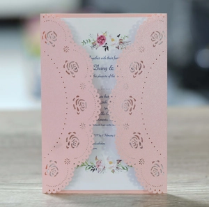 Detail of pink laser-cut rose hollow invitation with floral inner card on wood table