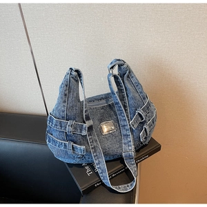 Close-up of washed blue denim tote with adjustable buckled straps and metal label
