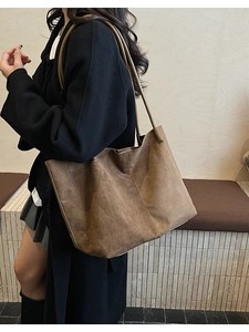 Détail d'un grand sac cabas en daim marron porté à l'épaule par un mannequin pour un look décontracté