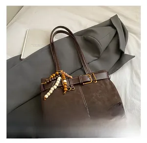 Détail d'un sac cabas vintage marron foncé avec coutures contrastées et perles en bois