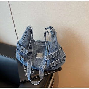 Detailed view of washed blue denim messenger bag with adjustable straps and metal buckles