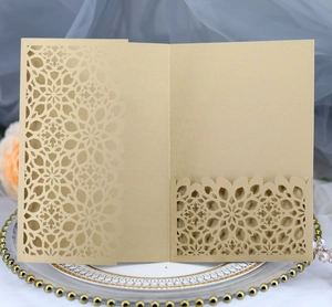 Detail of champagne gold laser-cut invitation with intricate floral hollow pattern