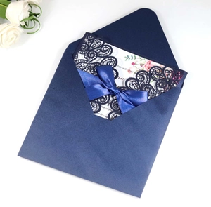 Detail of laser-cut peacock lace wedding invitation with navy envelope and floral insert