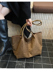 Détail du sac cabas en daim marron avec couture décorative et anses rondes