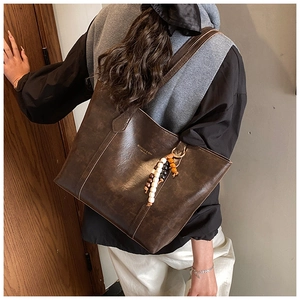 Detail of vintage brown tote bag texture with brand logo and decorative wood beads