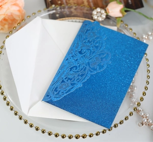 Macro shot of blue glitter laser-cut lace invitation cover with elegant floral patterns