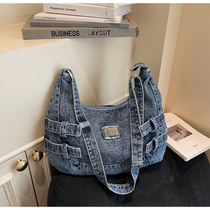Close-up of vintage washed denim tote bag featuring adjustable buckles and frayed metal plate