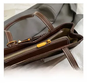 Détail de vue de dessus du sac à main en cuir marron foncé avec fermeture éclair dorée et coutures