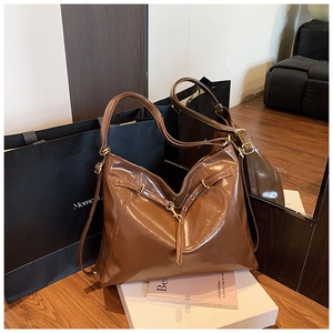Detail of vintage brown oil wax leather tote bag with glossy finish and gold metal hardware
