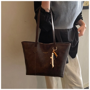 Detail of vintage brown tote bag with beaded tassel and gold lettering branding
