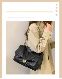 Detail of black quilted leather texture with gold square lock and chain shoulder strap