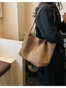 Sac fourre-tout en daim marron porté par un mannequin avec un manteau noir pour le style