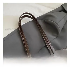 Détail du sac rétro en cuir marron avec surpiqûres blanches, boucle dorée et perles