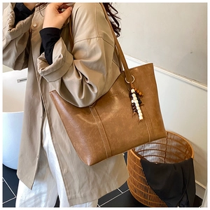 Detail of tan brown PU leather tote bag featuring colorful wooden beads and embossed logo