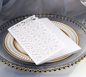 Macro detail of white laser-cut floral wedding invitation card on elegant glass plate