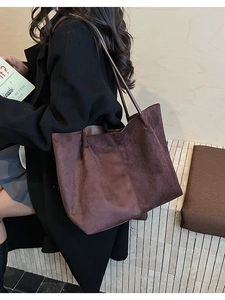 Vue latérale du sac cabas en daim marron foncé porté avec un manteau long pour le bureau