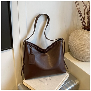 Detail of dark brown leather tote bag showing side drawstring and smooth texture