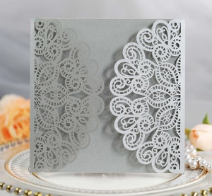 Macro shot of silver pearl laser-cut invitation card with intricate lace hollow patterns