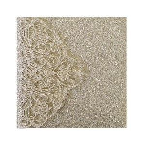 Macro shot of gold glitter laser-cut floral lace detail on wedding invitation cover