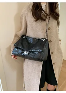 Close-up of black quilted chain tote bag worn with a beige wool coat for chic autumn style
