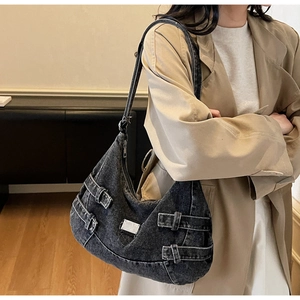 Close-up of black washed denim crescent bag with retro buckle straps on the side