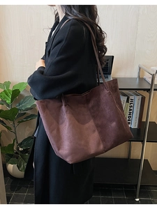 Vue détaillée du grand sac cabas en daim marron foncé porté à l'épaule pour le bureau