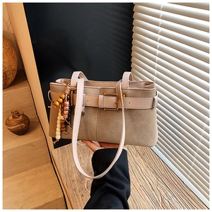 Détail du sac bandoulière vintage kaki avec boucles en métal et pompon en bois