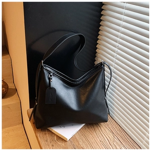Detailed close-up of a matte black leather crossbody bag with light and shadow effects