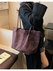 Gros plan d'un grand sac cabas en daim bordeaux porté à l'épaule pour un style décontracté
