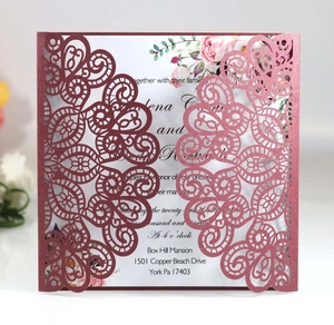 Macro view of burgundy laser-cut wedding invitation with elegant floral insert card