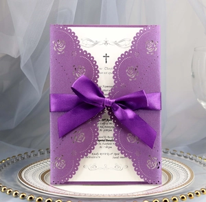 Detail of laser-cut purple floral wedding invitation with silk bow and inner card