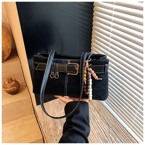 Détail d'un sac cabas en daim noir avec surpiqûres blanches et boucle vintage