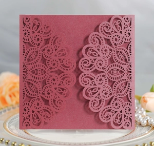 Macro shot of laser-cut burgundy wedding invitation with intricate lace hollow details