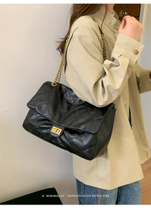 Detailed side view of black quilted leather tote bag with gold chain strap on model