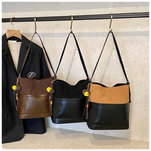 Three vintage bucket bags with fringe charms hanging on a metal rack in a studio