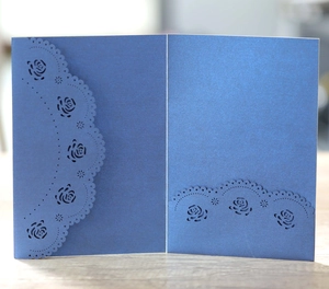 Détail de l'invitation de mariage bleue découpée au laser avec motif de rose nacrée