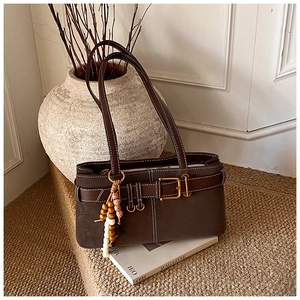 Détail d'un sac porté épaule marron vintage avec surpiqûres blanches et boucle dorée