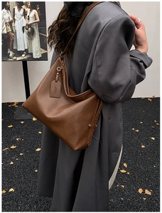 Detail of a brown leather hobo bag with a circular hardware ring and logo tag