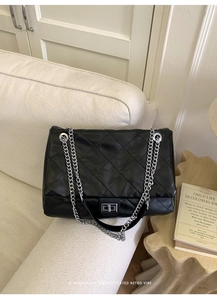 Close-up of quilted black leather tote featuring silver chain strap and metal lock closure