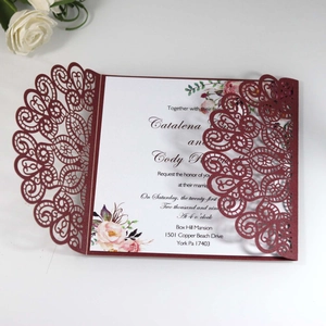 Detail of laser-cut floral peacock lace wedding invitation in burgundy cardstock