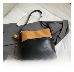 Detail of vintage two-tone bucket bag with suede texture and tassel charm on bed