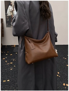 Detailed view of a brown leather shoulder bag with metallic studs and brand tag