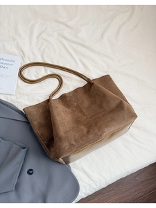 Gros plan du sac cabas en daim marron avec détails en cuir et style vintage minimaliste